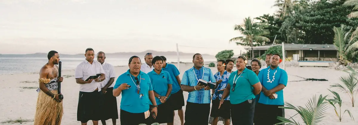 A group in traditional dress on a Fijian beach