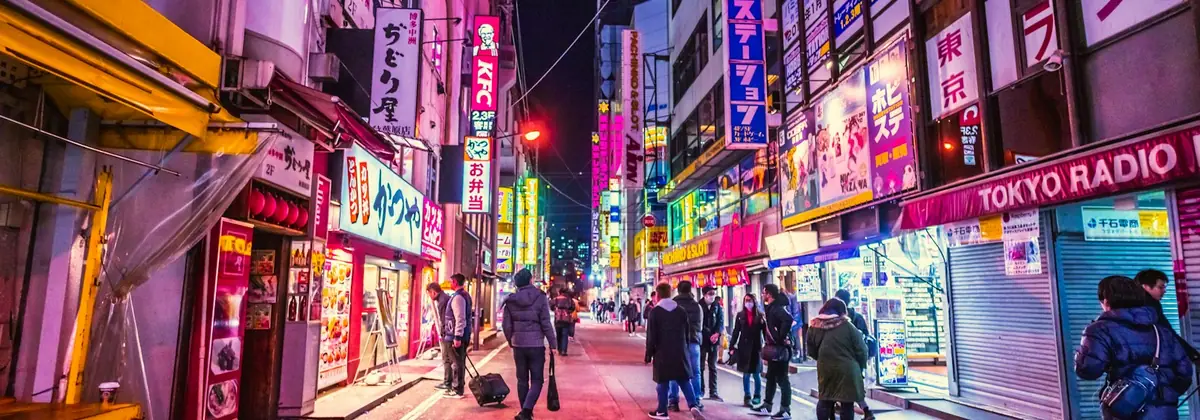 Travellers on a neon-lit Tokyo street
