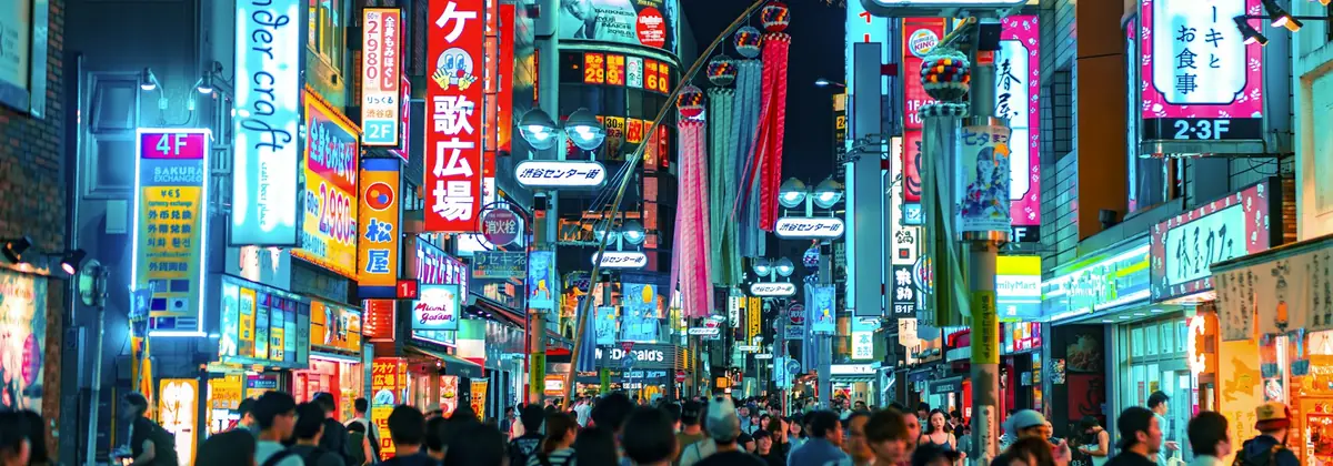 Travellers on a neon-lit Tokyo street